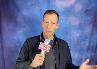 Kurt Kellerer Epas Presseagentur mit einem Handmikrofon vor einem blau-verlaufenden Hintergrund